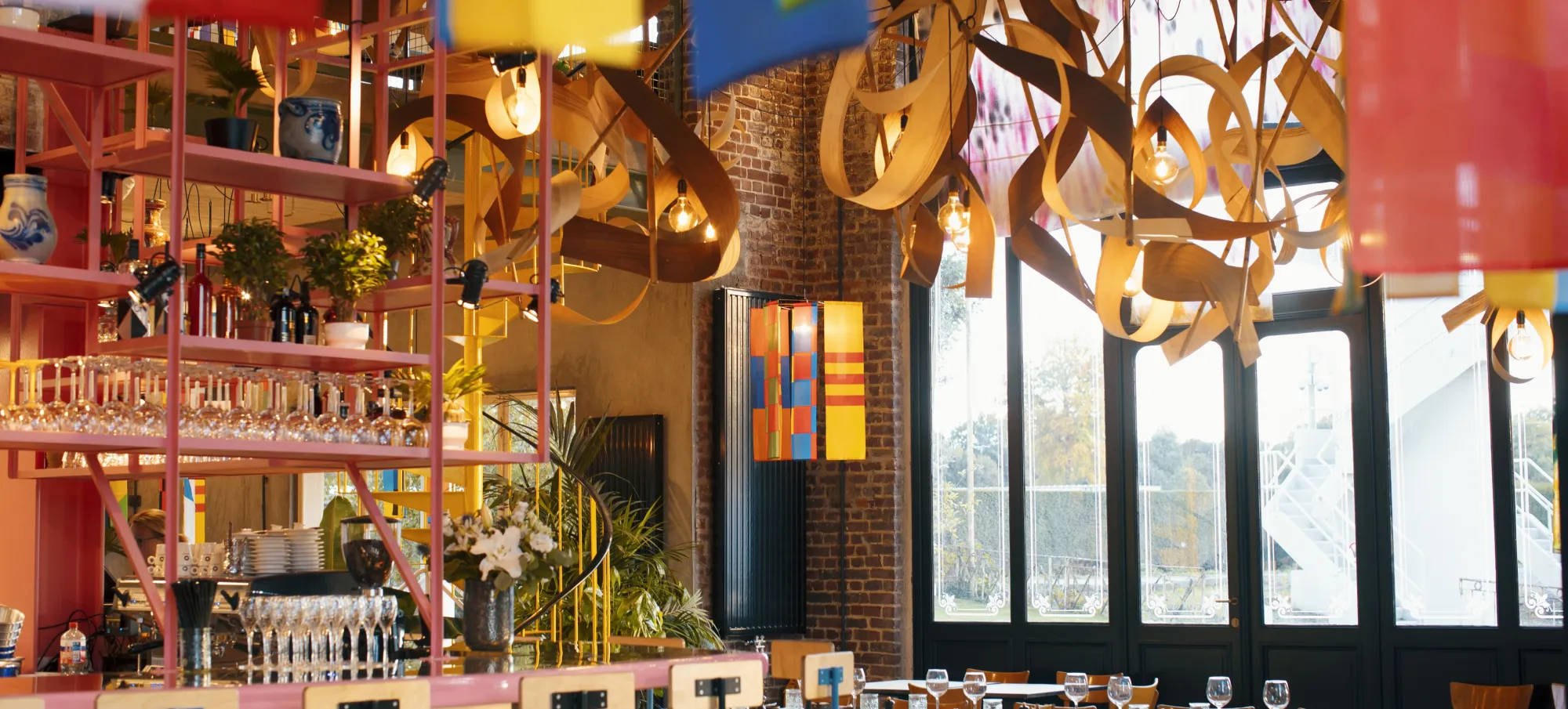 L'intérieur du Pesage — sculpture suspendue en bois, mur rose corail, salle ouverte sur la forêt